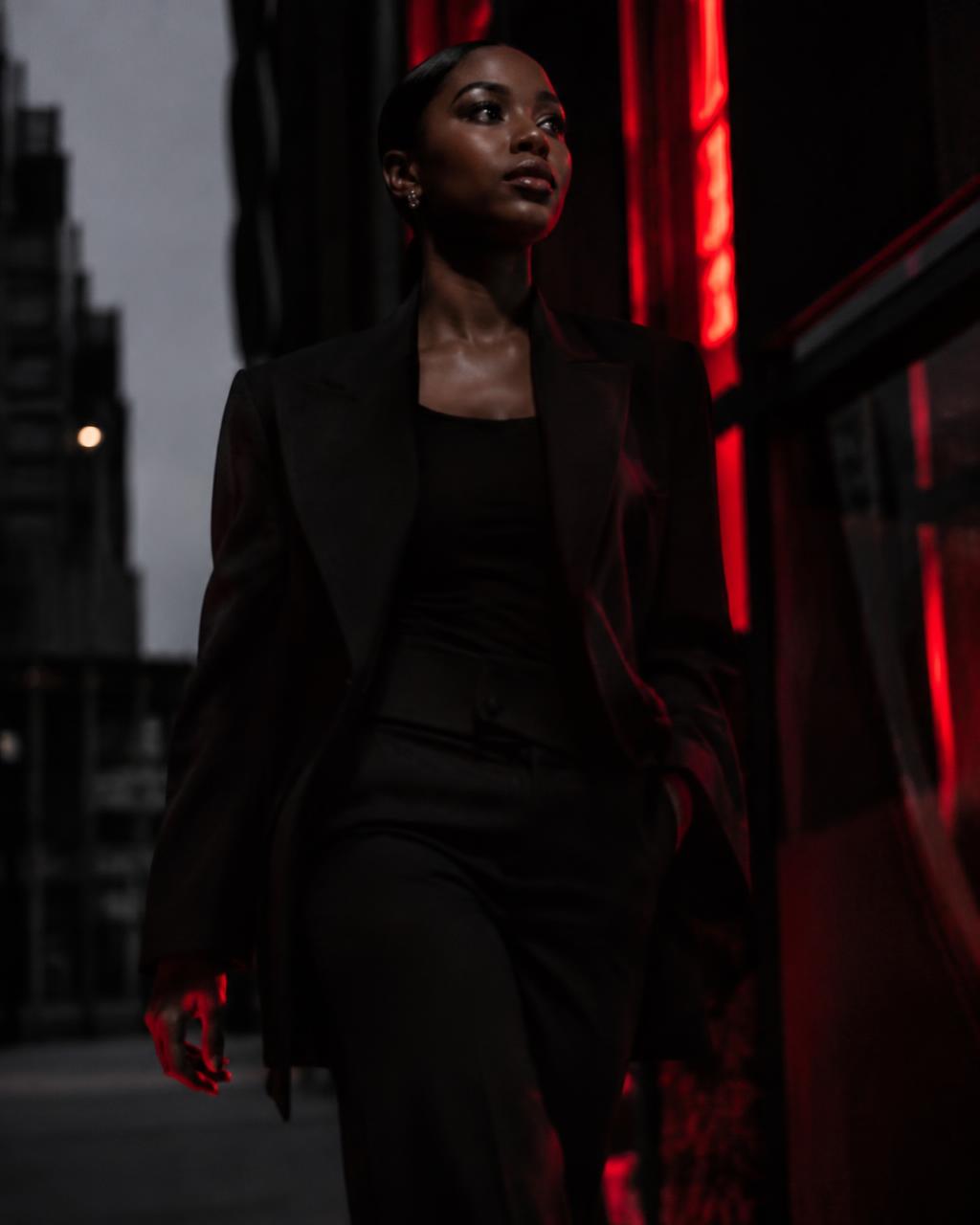 Woman in a black suit walking through the city at night